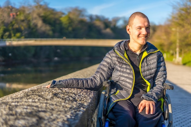 A disabled person in a wheelchair in a park at sunset next to a river