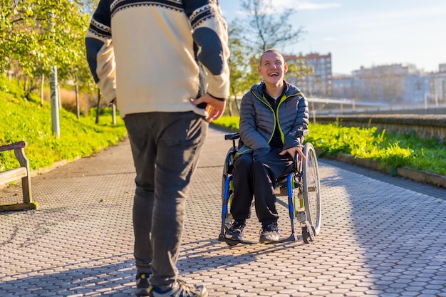 Persona disabile su sedia a rotelle che sorride con un membro della famiglia che fa una passeggiata in un parco