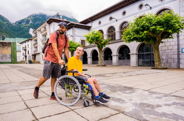 Un disabile in sedia a rotelle che passeggia per la piazza del paese con un amico