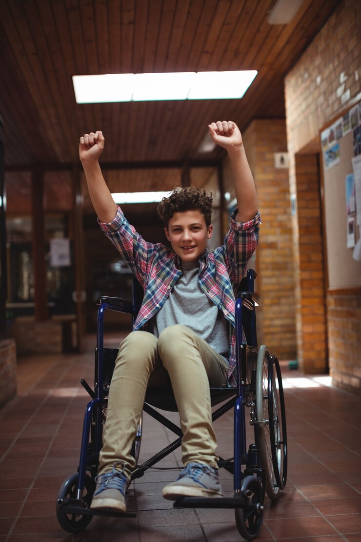 Photo disabled schoolboy on wheelchair in corridor at school