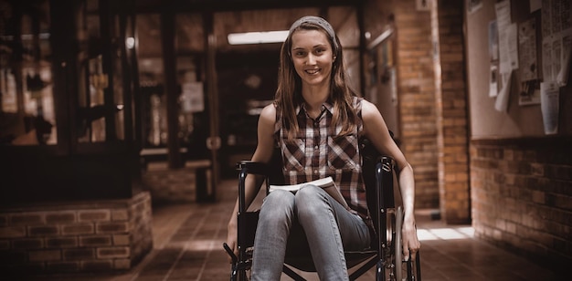 Disabled schoolgirl on wheelchair in corridor at school