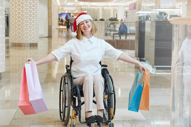 A disabled woman wearing a Santa hat with shopping bags