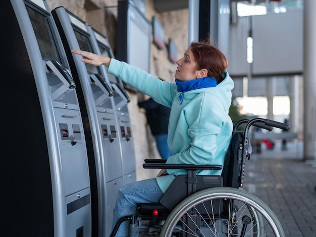 Photo disabled woman on wheelchair at ticket vending machine