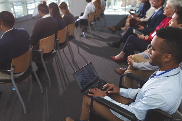 Photo disabled young businessman using laptop during seminar