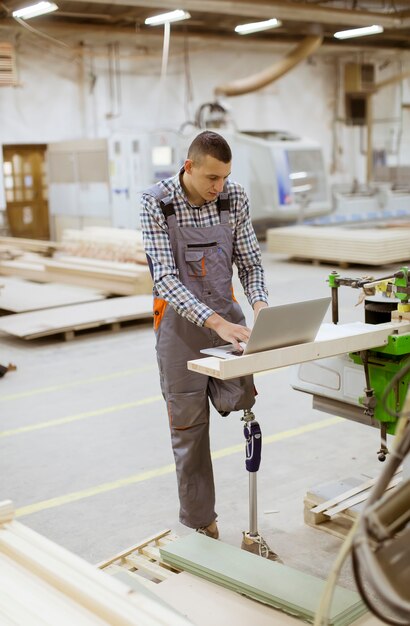 Disabled young man with an artificial leg is working at the furniture  factory