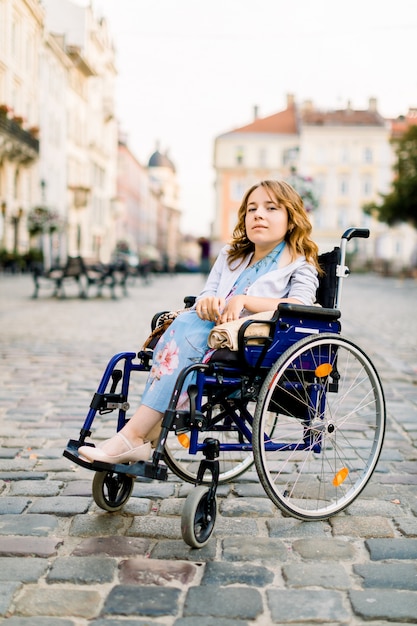 Disabile giovane donna in abito blu, seduto su una sedia a rotelle