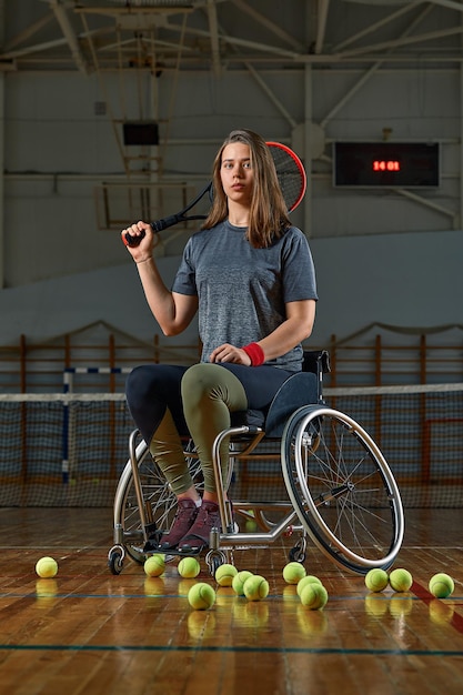 Disabled young woman on wheelchair playing tennis on tennis court