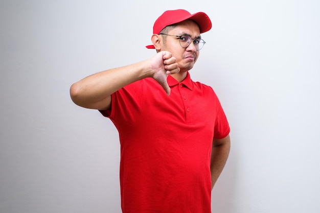 disappointed asian delivery man in red tshirt and cap express dislike and bad attitude
