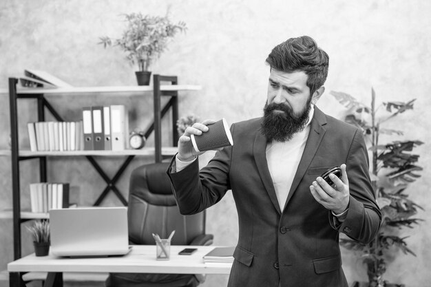 Disappointed businessman checking empty disposable coffee cup during office break takeaway