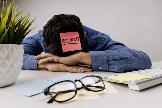 Photo disappointed businessman is sleeping near laptop and glasses burnout concept