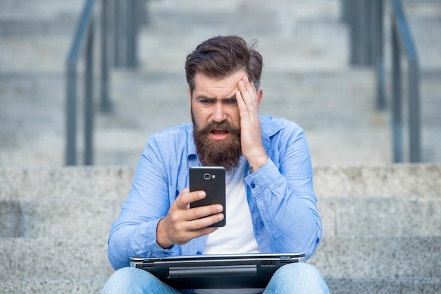 disappointed guy lost bet upset guy checking up betting results in mobile phone making bet