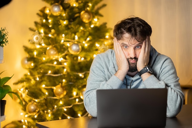 A disappointed man sits in front of a computer on New Year's Eve in the office