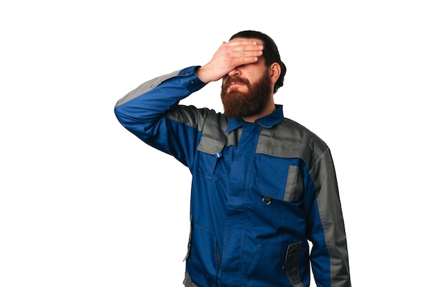 Disappointed man wearing handyman uniform is and makes facepalm gesture