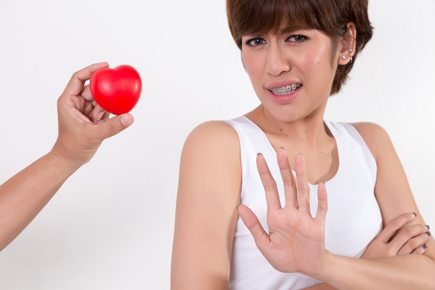 Disappointed woman rejecting the red heart of her boyfriend.