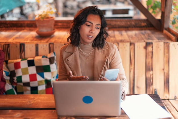 Disappointed young business Indian woman looking at mobile phone with stressful looking