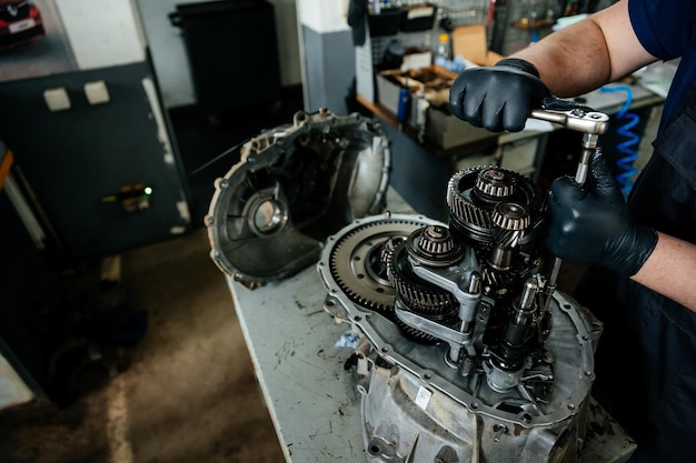 Photo a disassembled gearbox in the hands of an experienced car mechanic who repairs broken mechanisms and parts in a car