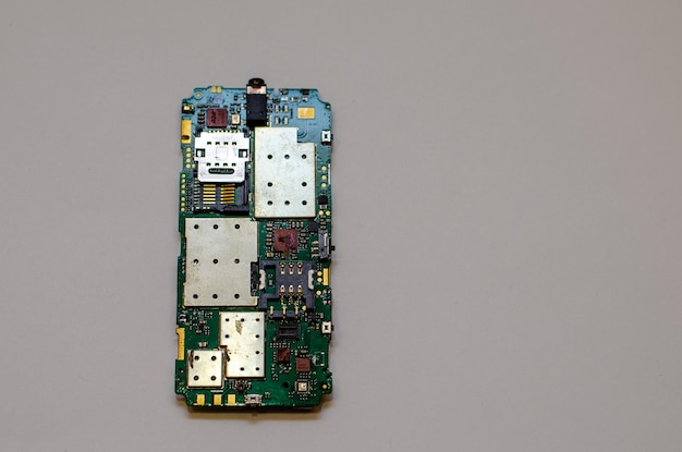 Disassembled mobile phone on the table of a mechanical engineer during repair Tweezers and screwdriver for repairing electronic gadgets on a white background