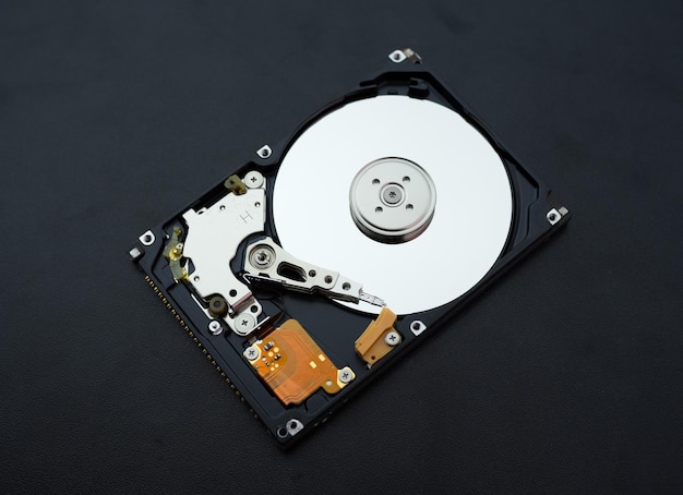 写真 分解された開いたハードディスクドライブ コンピューターまたはラップトップの hdd が暗いマットな表面に置かれている コンピューターのハードウェアおよび機器 ハードディスクのデータストレージ