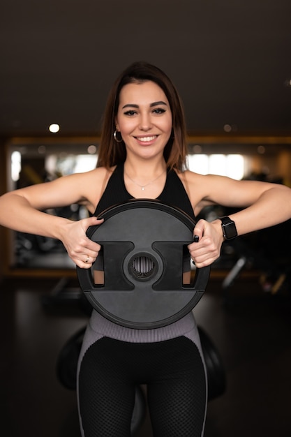 A disc for a barbell in the hands of a woman The Right Young Strength Trainer