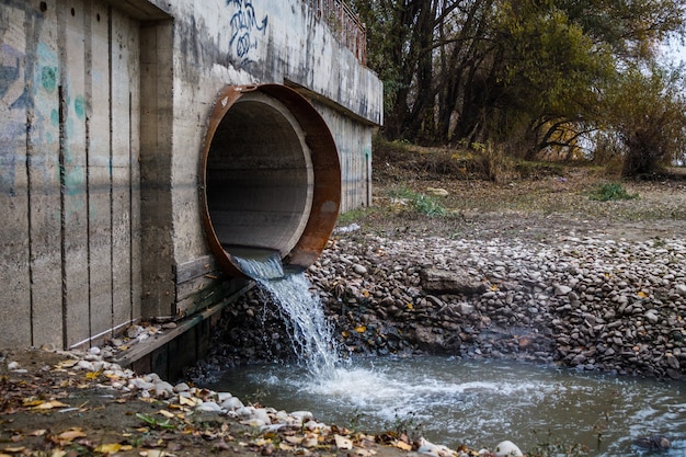 The discharge of wastewater into the river through a large rusty pipe