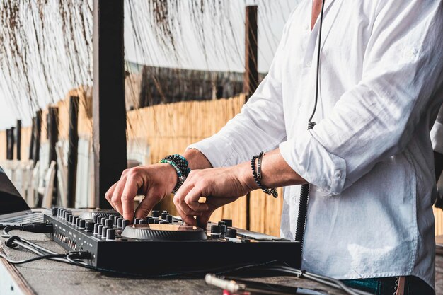 Discjockey die muziek speelt voor toeristen op clubfeest buiten op het strand Dj bij muziek live evenement Live evenement muziek en leuk concept Entertainment en feestconcept Focus op handen