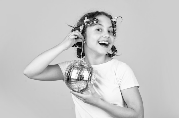 Photo disco ball decoration lovely girl with disco ball fashion girl posing in curlers on yellow wall saturday night and disco ball baby shower party lets have fun on retro party holiday objects