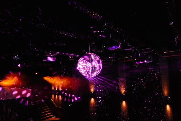 Disco ball hanging on the ceiling of the disco rays of light\
are reflected from it