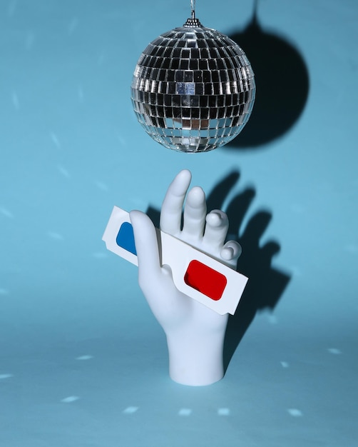 Discobal en hand met 3D-bril op blauwe achtergrond Minimalisme party concept