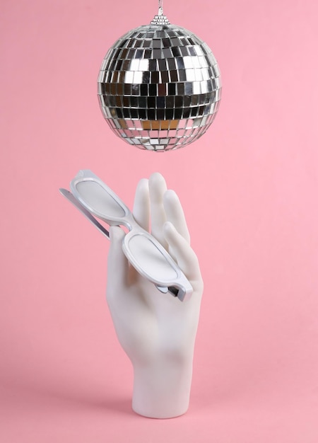 Discobal en hand met bril op roze achtergrond Minimalisme party concept