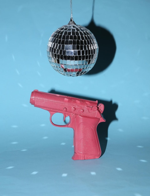 Discobal en pistool op blauwe heldere achtergrond Minimalisme party concept