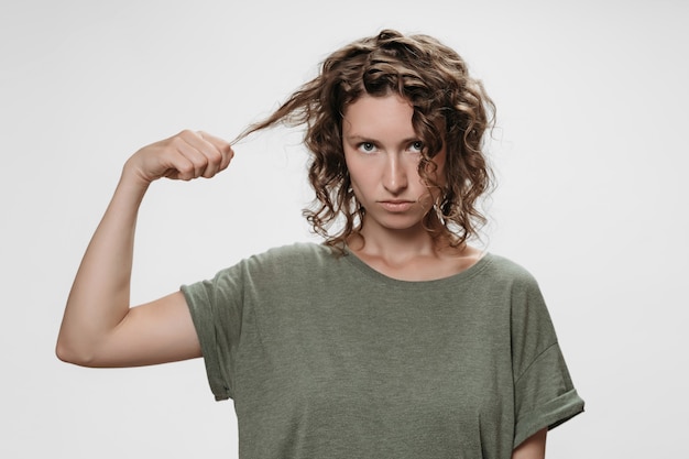 Photo discontent curly brunette woman, frowns face with displeasure