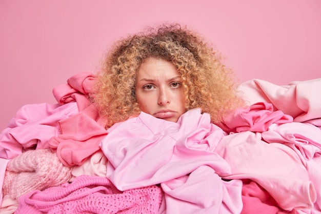 Photo discontent curly haired woman looks sadly at camera