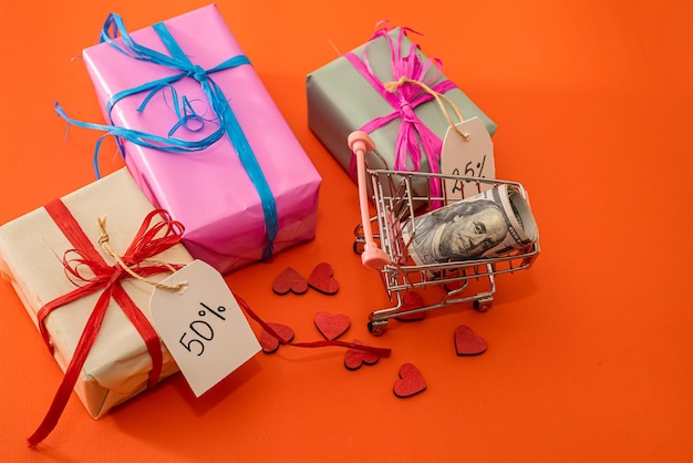 Discount gifts lie next to a shopping cart in which dollars on background