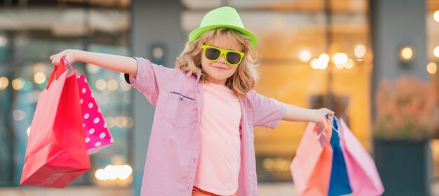 Discounts and sales happy kid boy with shopping bags little child on shopping trends and brands