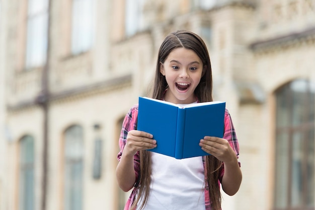 新しい何かを発見してください。幸せな子供は屋外で本を読みます。口を開けて興奮した本の虫。学校図書館。文学を読む。識字教育。児童書。 Bookstory。その本の時。