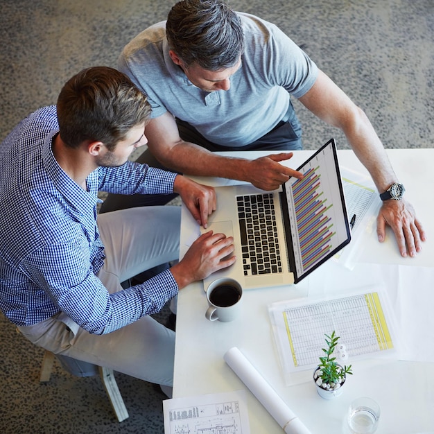 Discussie over laptopgegevens en teamwerk van zakenmensen aan statistische analyse, boekhouding of financieel onderzoek wijzend gebaar samenwerking en bovenaanzicht van accountantsteam dat werkt aan beoordeling van grafiekanalyse