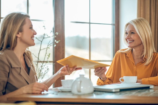 Discussie. Twee vrouwen praten en bespreken iets terwijl ze aan tafel in een café zitten