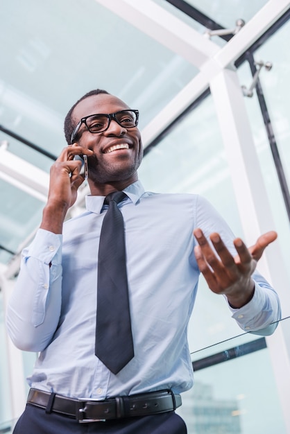 Discussing business. Low angle view of confident young African man in shirt and tie