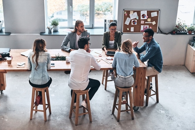 Discutere nuove idee. vista dall'alto dei giovani moderni che lavorano insieme mentre sono seduti in ufficio