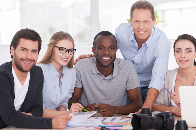 Discussing new project together. Group of cheerful business people sitting together at the table and discussing something