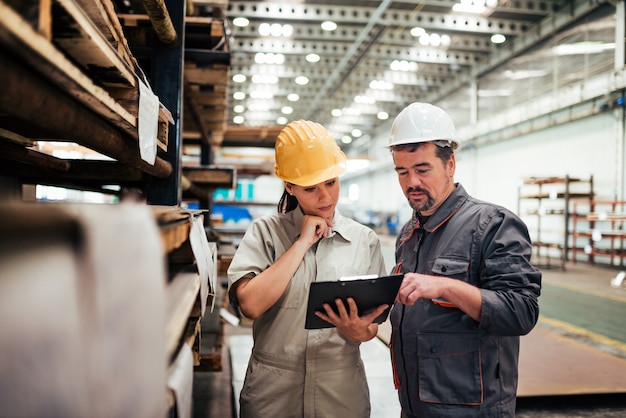 Discussing with supervisor at heavy industry factory.