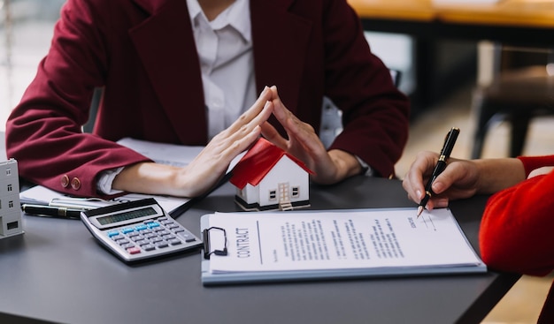 Discussion with a real estate agent House model with agent and customer discussing for the contract to buy get insurance or loan real estate or property