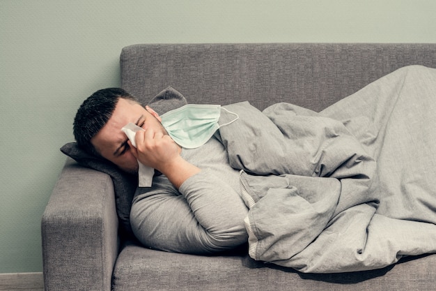 疾患。家で乾杯。若い男は病気で、自宅で治療されます。鼻をナプキン、鼻水に吹き込みます。感染、流行、バチルスキャリア。