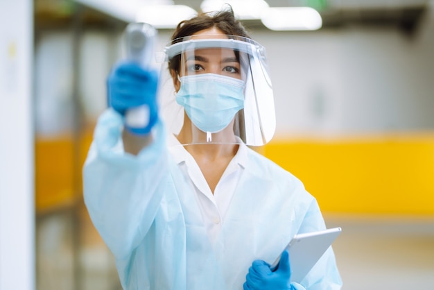 Photo disease control expert with an infrared thermometer equipment to check the temperature at office.