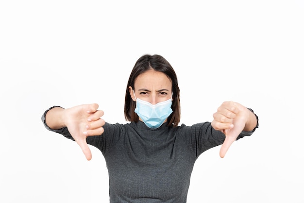 Disgusted hispanic woman wearing a face mask with the thumbs down