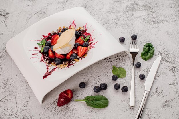 Dish of Camembert cheese with a strawberry and blueberries Top view