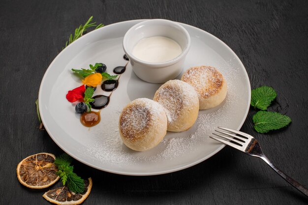 dish of cheese pancekes with syrup on wooden background