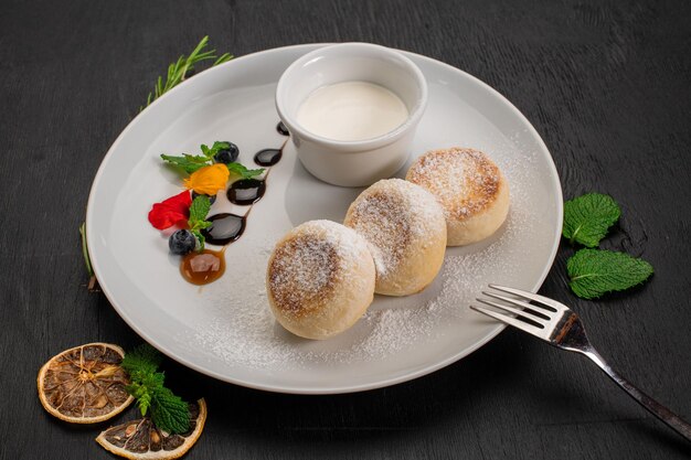 Dish of cheese pancekes with syrup on wooden background