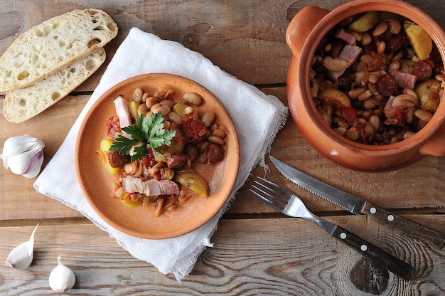 Piatto cotto in una pentola con patate, fagioli, affumicato in una pentola di terracotta