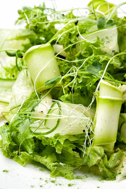 a dish of cucumbers, lettuce and microgreen in a white plate close-up